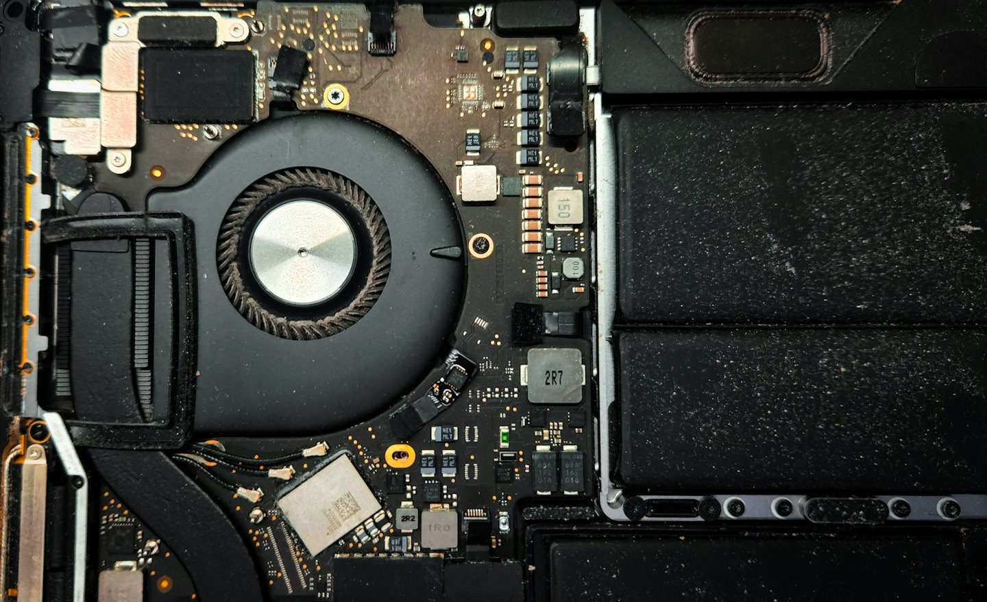 Dusty electronic components inside an opened laptop computer.
